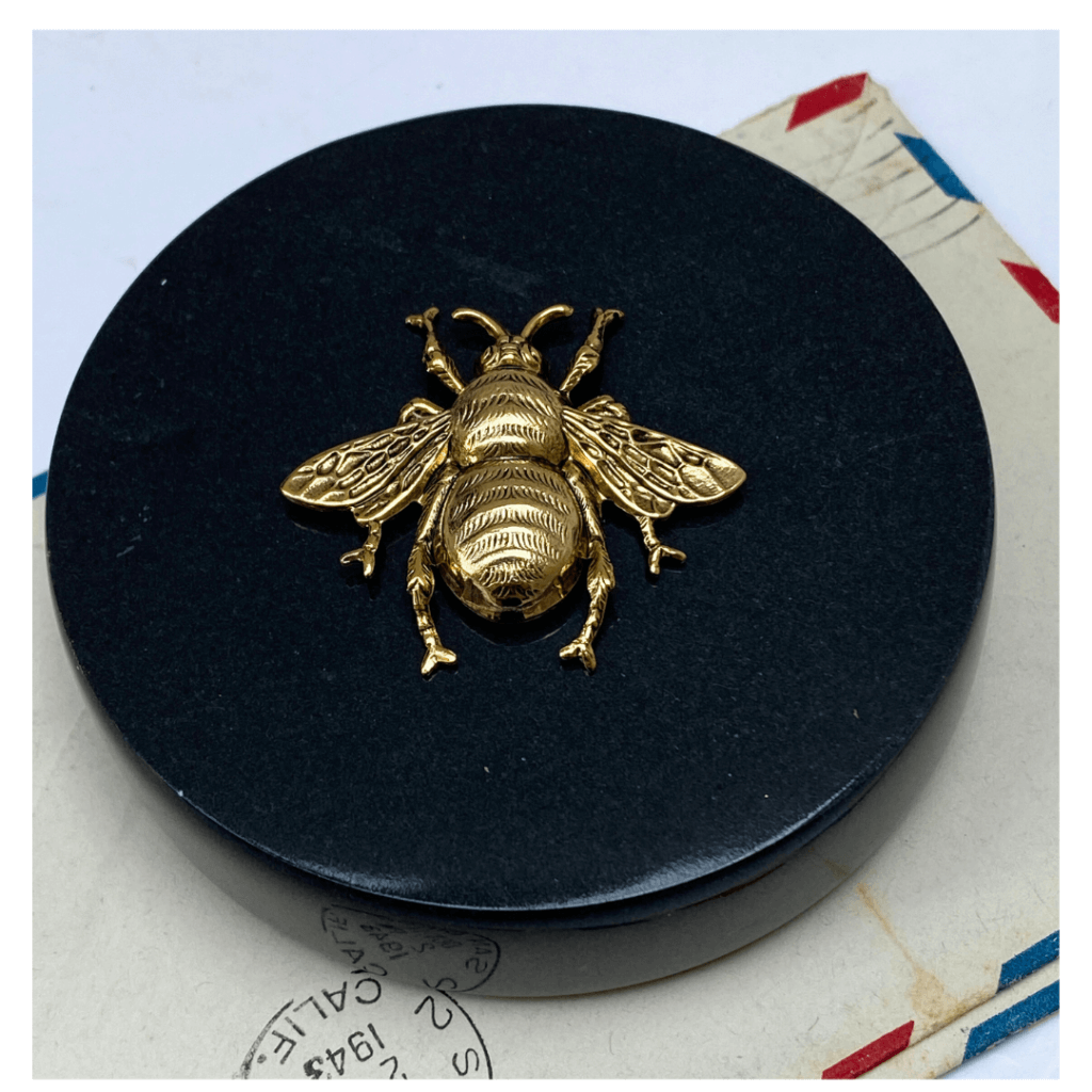black round paperweight and gold bee